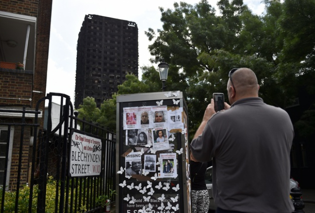 ''Grenfell Tower'' ugunsgrēkā pazudušo cilvēku fotogrāfijas pie nodegušās ēkas. Foto: Reuters-LETA