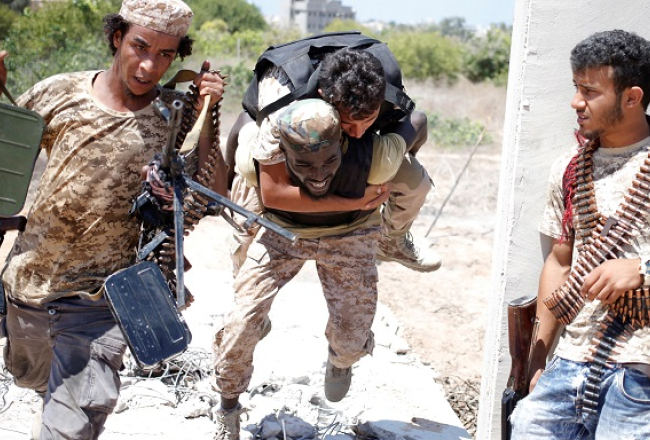Lībijas armijas karavīri no apšaudes iznes ievainotu biedru. Foto: Reuters/LETA