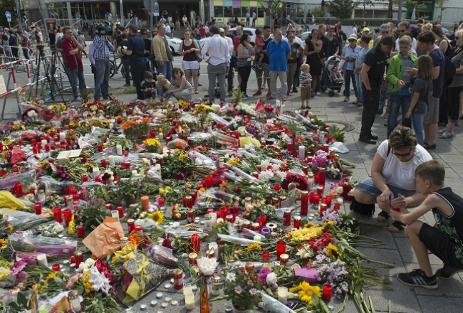 Cilvēki liek ziedus pie Minhenes tirdzniecības centra. Foto: AFP/LETA