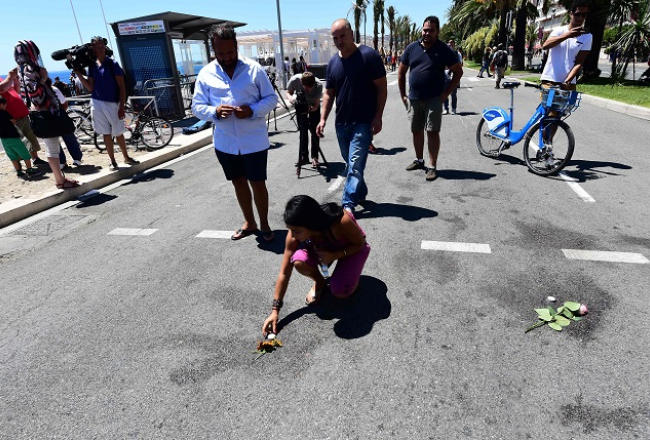 Sieviete noliek ziedus un sveces katrā vietā Angļu promenādē, kur tika nogalināts kāds cilvēks. Foto: AFP/LETA