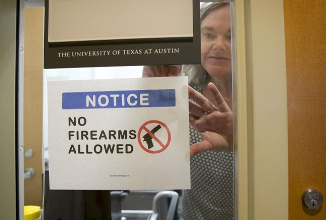 Teksasas universitātes Ostinā antropoloģijas profesore Paulīne Stronga pie sava kabineta durvīm piestiprina norādi, ka te nedrīkst ienākt ar ieročiem. Foto: AP/LETA
