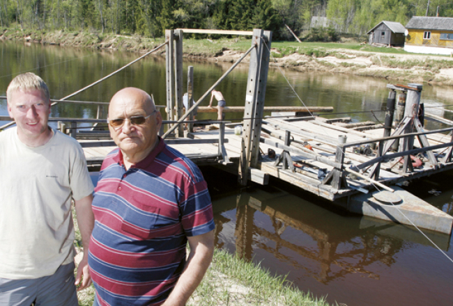 Laimonis Gradovskis (pa labi) atnācis apraudzīt uzbrauktuves remontdarbus, ko pēc negaidītajiem pagājušā rudens plūdiem un šāpavasara paliem veic jaunais pārcēlājs, viņa dēls Mareks. Līgatnes prāmis darbu atsāka šonedēļ. Foto — Mārtiņš Zilgalvis, F64