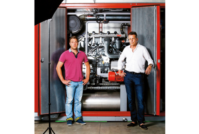 UPB koncerna vadītājs Uldis Pīlēns (pa labi) un UPB Energy valdes loceklis Māris Dzirnieks stāv pie tipiska savas ražotnes produkta — šī koģenerācijas iekārta tiks vesta uz Vāciju.