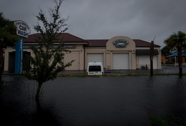 Plūdu ūdens ieskauj automašīnu mazgātavu Floridā, Bonita Springs.