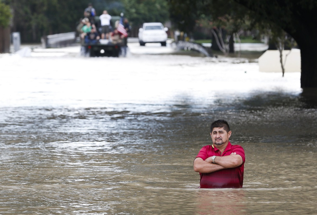 Vīrietis stāv uz applūduša ceļa pie tilta Hjūstonā. Foto: AP/LETA