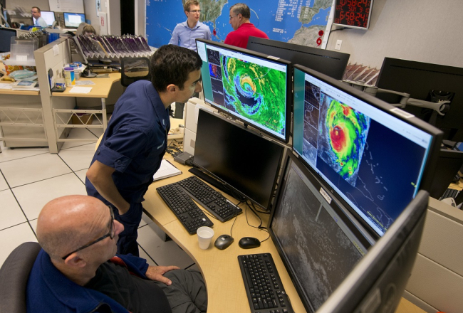 Vecākais viesuļvētru speciālists Liksions Avila (no kreisās) un Nacionālās okeānijas un atmosfēras pētījumu pārvaldes operatīvās nodaļas darbinieks Fils Manugjans seko radaram, kas rāda viesuļvētras "Irma" pārvietošanos.