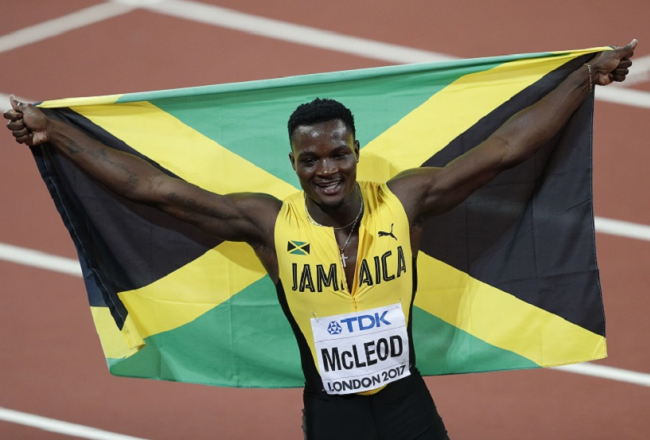 Jamaikas skrējējs Omars Makleods svin uzvaru šovasar 110 m skrējienā. Viņam rokās Jamaikas karogs. Foto: AFP/LETA