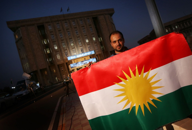Irākas kurds tur Kurdistānas karogu pie Kurdistānas parlamenta ēkas Arbilā. Foto: AFP/LETA