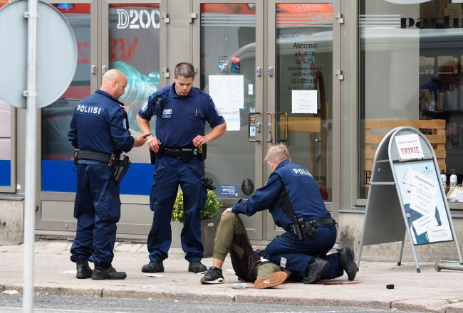 Turku policisti pie viena no sadurtajiem cilvēkiem. Foto: AFP/LETA