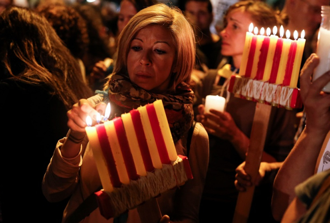Sieviete demonstrācijā par Katalonijas neatkarību tur sveces reģiona karoga krāsās. Foto: AFP/LETA