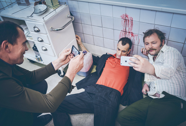 Amizants brīdis filmēšanas laukumā — aktieri sevi iemūžina neikdienišķi asiņainos pašģīmjos.
Foto — Lauris Vīksne