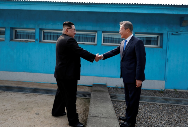 Dienvidkorejas prezidents Muns Džēins sarokojas ar Ziemeļkorejas līderi Kimu Čenunu uz abu valstu robežas. Foto: Reuters/LETA