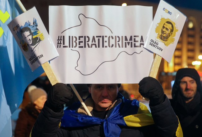 Ukrainas aktīvists rokās tur plakātu ar uzrakstu "Brīvību Krimai", aicinot atbrīvot Krievijas cietumos smokošos Krimas aktīvistus. Foto: EPA/LETA
