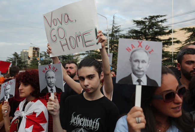 7. augustā Gruzijas galvaspilsētā aktīvisti piedalījās protesta mītiņā pret Krievijas politiku Gruzijā. Viņi šajā dienā atcerējās pirms 10 gadiem kritušos gruzīnu karavīrus īsajā karā ar Krieviju. Demonstranti tur rokās plakātus ar uzrakstu "Vova, ej mājās!", kā arī Krievijas prezidenta Vladimira Putina foto ar rupju vārdu. Foto: EPA/LETA