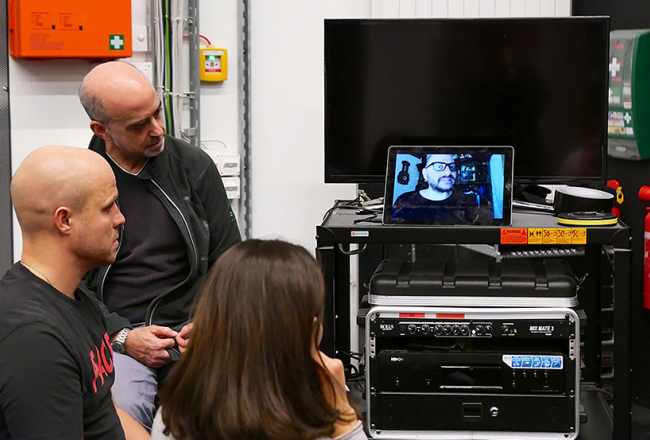 No kreisās: Jevgēnijs Kulagins, tulks Markuss Vailers un soprāns Ruzana Mantašjana skatās Kirila Serebreņņikova atsūtīto videokomentāru.
Foto — The New York Times