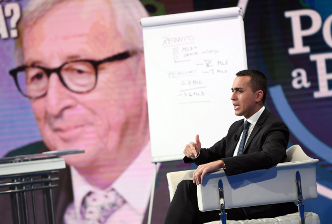 Itālijas premjerministra vietnieks un ekonomiskās attīstības ministrs Luidži Di Maio kādā TV šovā atbild uz EK prezidenta Žana Kloda Junkera (fonā) prasībām ievērot ekonomiski pamatotu valsts budžetu. Foto: Scanpix