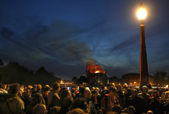 Parīzes iedzīvotāji vēro ugunsgrēku Parīzes Dievmātes katedrālē. Foto: EPA/IAN LANGSDON