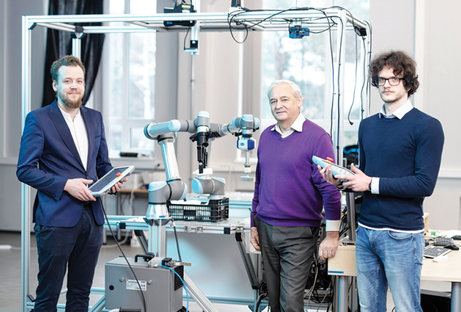 Elektronikas un datorzinātņu institūta direktors, vadošais pētnieks Modris Greitāns (vidū), pētnieks Jānis Ārents (pa kreisi) un zinātniskais asistents Pēteris Račinskis kopā ar pašu radīto gudro robotu.
Foto — Reinis Hofmanis