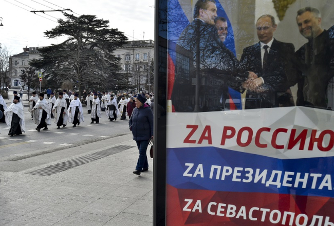 Krievijas preizticīgo baznīcas gājiens Krimā šogad janvārī Sevastopolē. Plakātā redzams Krievijas prezidents Putins, kurš spiež roku Maskavas ieceltajiem Krievijas okupēto reģionu vadītājiem Ukrainas austrumos. Foto - AP/Scanpix/LETA
