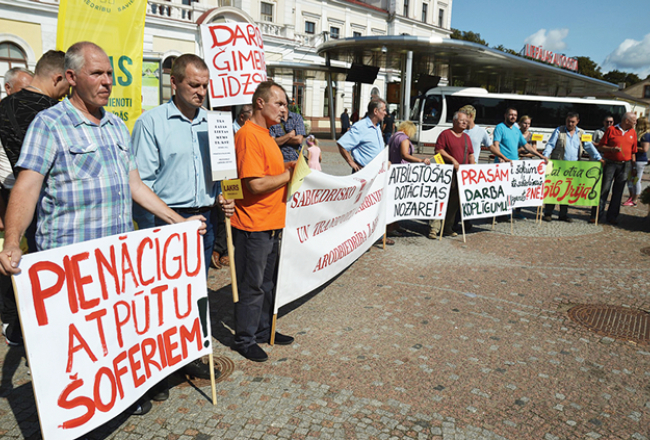 Šoferu pikets Liepājā 2018. gada augustā. Nākamā gada pavasarī viņi bija gatavi arī streikot, taču tiesa arodbiedrības pieteikumu atzina par nelikumīgu. Galvenās streika prasības bija lielāka alga un sabalansēts darba grafiks.
Foto — Egons Zīverts