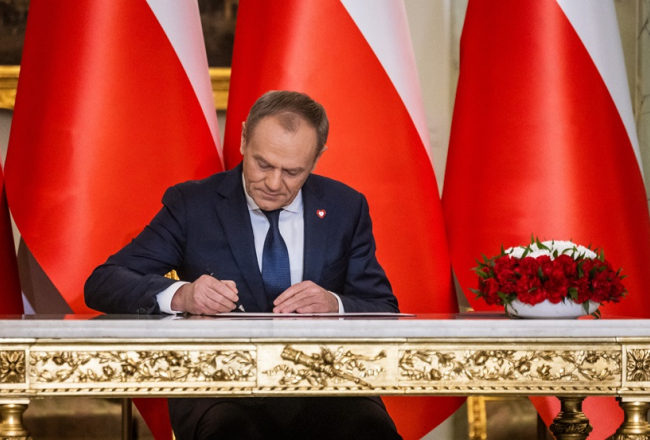 Jaunais Polijas premjerministrs Donalds Tusks 13. decembrī prezidenta pilī Varšavā paraksta dokumentu oficiālas zvēresta nodošanas ceremonijas laikā. Foto - Wojtek Radwanski/AFP