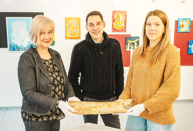 Aizputes Novadpētniecības muzeja vadītāja Jolanta Berga (no kreisās), pētnieks Andris Vasiļevskis un krājumu glabātāja Iveta Zomberga rāda pērn atgūto mamuta kaulu.