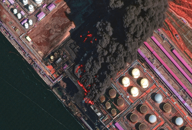 No satelīta uzņēmtā attēlā redzams plašs ugunsgrēks Ustjugas ostā 27. martā.