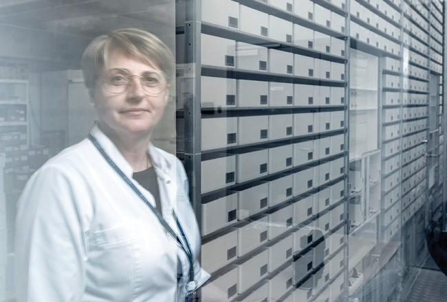 Rīgas Austrumu slimnīcas Aptiekas dienesta vadītāja Laila Eglīte rāda automatizētu zāļu skapi, kas ievestos medikamentus šķiro un izsniedz pēc vajadzības, kā arī uzmana to derīguma termiņu.