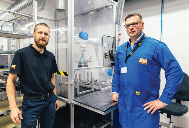 Produktivitātes rādītājus HansaMatrix Ventspils ražotnē uzlabo, izmantojot arī robotu roku darbu, rāda Edžus Siliņš (pa kreisi) un Dāvis Šnikvalds.