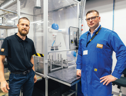 Produktivitātes rādītājus HansaMatrix Ventspils ražotnē uzlabo, izmantojot arī robotu roku darbu, rāda Edžus Siliņš (pa kreisi) un Dāvis Šnikvalds.