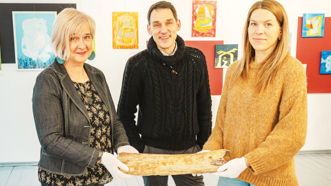 Aizputes Novadpētniecības muzeja vadītāja Jolanta Berga (no kreisās), pētnieks Andris Vasiļevskis un krājumu glabātāja Iveta Zomberga rāda pērn atgūto mamuta kaulu.