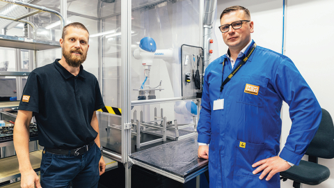 Produktivitātes rādītājus HansaMatrix Ventspils ražotnē uzlabo, izmantojot arī robotu roku darbu, rāda Edžus Siliņš (pa kreisi) un Dāvis Šnikvalds.