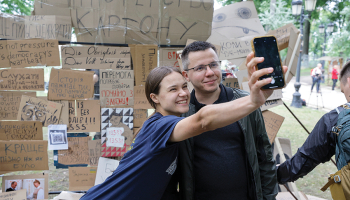 Jaunieši Kijivā pozē pie simboliskas sienas ar plakātiem, kuri tika izmantoti protestos pret pretkorupcijas iestāžu neatkarības likvidēšanu.