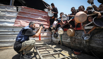 Anass Fteiha 24. jūlijā fotografē cilvēkus, kas ieradušies saņemt ēdienu. Šis attēls viņam radījis daudzas problēmas.
Foto — Khames Alrefi / Anadolu Agency