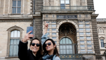 Tūristes pie izsistā loga, pa kuru laupītāji iekļuva Luvras muzejā.