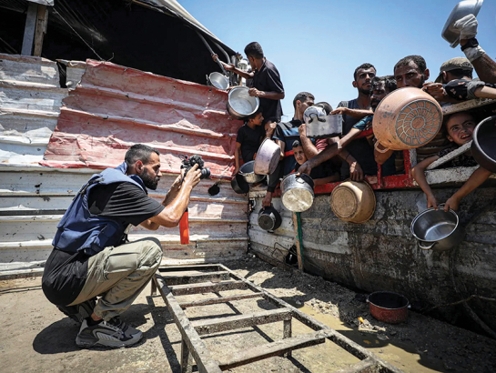 Anass Fteiha 24. jūlijā fotografē cilvēkus, kas ieradušies saņemt ēdienu. Šis attēls viņam radījis daudzas problēmas.
Foto — Khames Alrefi / Anadolu Agency