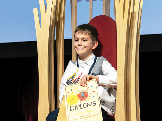 Čempionāta finālā Roberts izvēlējās fragmentu no Ilzes Skrastiņas grāmatas Kā iet? Normāli! un izteiksmīgi mainīja intonācijas, lai piešķirtu katram tēlam savu balsi. Foto — Kristians Luhaers