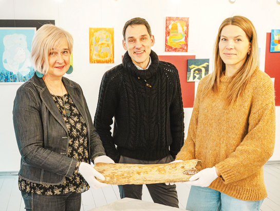 Aizputes Novadpētniecības muzeja vadītāja Jolanta Berga (no kreisās), pētnieks Andris Vasiļevskis un krājumu glabātāja Iveta Zomberga rāda pērn atgūto mamuta kaulu.