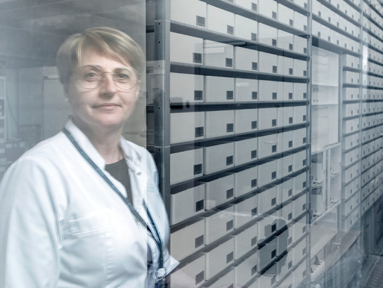 Rīgas Austrumu slimnīcas Aptiekas dienesta vadītāja Laila Eglīte rāda automatizētu zāļu skapi, kas ievestos medikamentus šķiro un izsniedz pēc vajadzības, kā arī uzmana to derīguma termiņu.