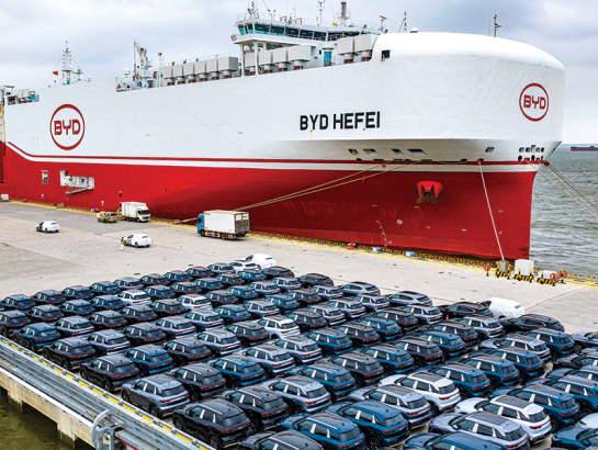 BYD elektroauto pirms iekraušanas kravas kuģī ostā pie Šanhajas.