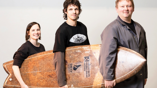 Koksnes institūta vadošā pētniece Ulla Milbreta (no kreisās), sēņu dēļa idejas autors, dizainers Lūkass Segliņš un vadošais pētnieks Mārtiņš Andžs ar pašu radīto šedevru, no «sēnēm» izaudzēto sērfošanas dēli.