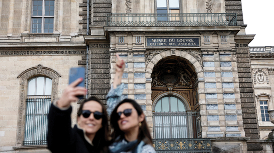 Tūristes pie izsistā loga, pa kuru laupītāji iekļuva Luvras muzejā.