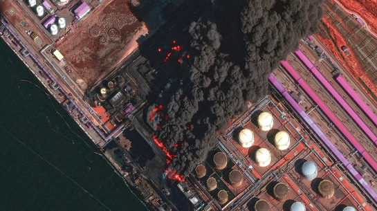 No satelīta uzņēmtā attēlā redzams plašs ugunsgrēks Ustjugas ostā 27. martā.