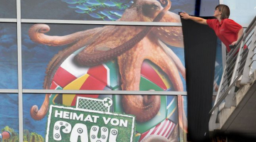 Akvārija darbiniece plakātam piestiprina melnu sēra lentu. Avots: AFP/LETA