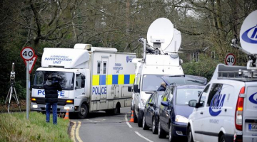 Britu policijas izmeklētāju busiņš un daudzo mediju automobiļi pie Borisa Berezovska mājas. Foto: EPA/LETA
