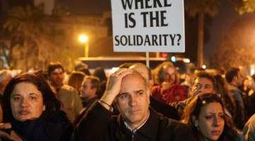Ceturtdienas vakarā daudz ļaužu piedalījās demonstrācijā pie Kipras valdības ēkas. "Kur ir solidaritāte?" vaicā plakātā bēdu sagrautie kiprieši. Foto: AFP/LETA
