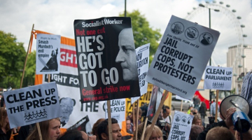 Protestētāji Londonā pauž attieksmi pret Mērdoka medijiem. Foto: AFP/LETA