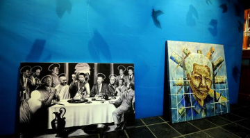 Izstādē Johannesburgā - glezna "Svētais vakarēdiens" (pa kreisi), ko radījis mākslinieks Dans Saimons, un "Mandela globālajā ikonā" - mākslinieks Daniels Mosako. Foto: AFP/LETA