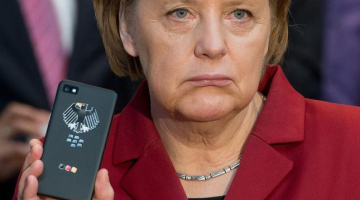 Vācijas kanclere Angela Merkele rāda savu telefonu. Foto: EPA/LETA
