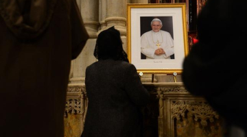 Lūdzēji baznīcā Ņujorkā pie Benedikta XVI fotogrāfijas. Foto: AFP/LETA